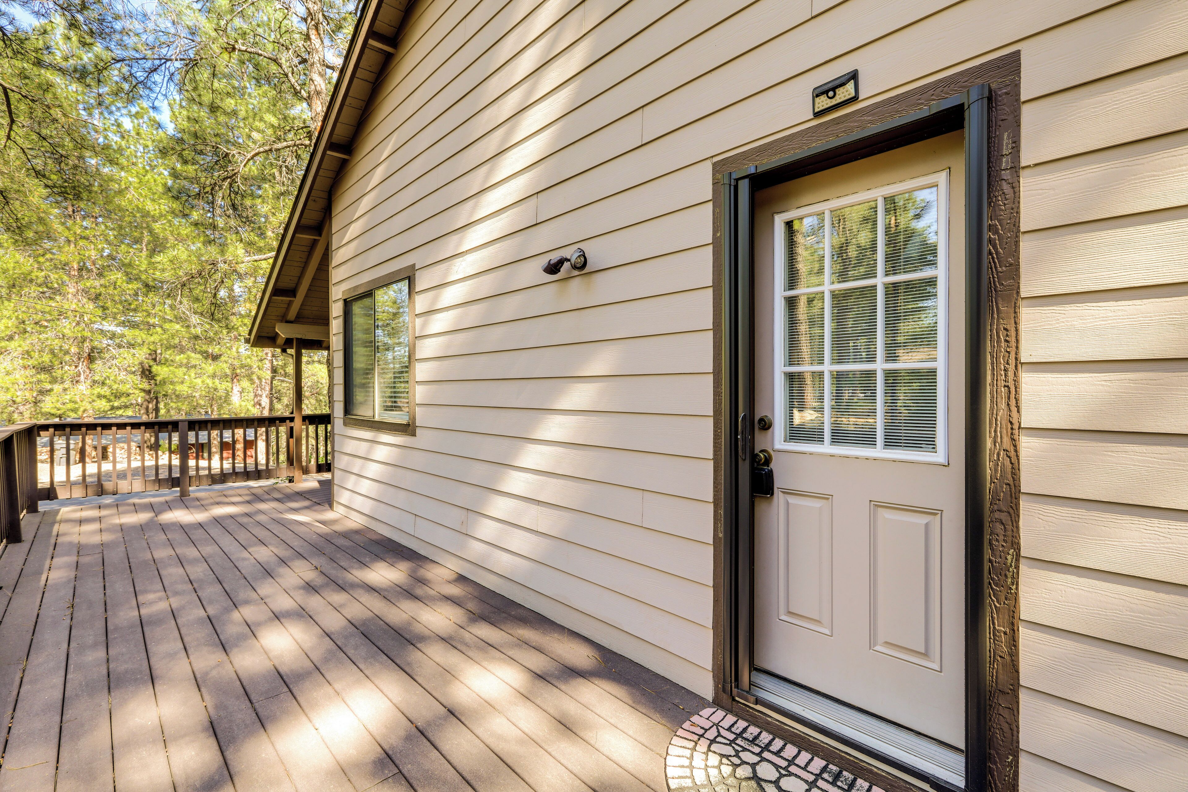 A wooden deck with a door and window, surrounded by trees.