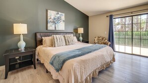 Una camera da letto con un letto grande, due lampade ai comodini, una ventola a soffitto, una finestra con vista e un quadro appeso al muro.