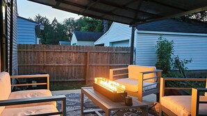 An outdoor patio with a fire feature, seating, and a covered area.