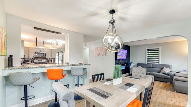 A modern kitchen with a central island, bar stools, and a dining table with chairs.