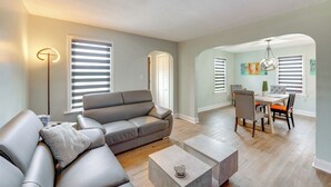 A modern living room with a gray sectional sofa, a coffee table, and a dining area with a table and chairs.