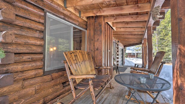 Eine Holzhütte mit Veranda, Glastür und Tisch mit Stühlen.