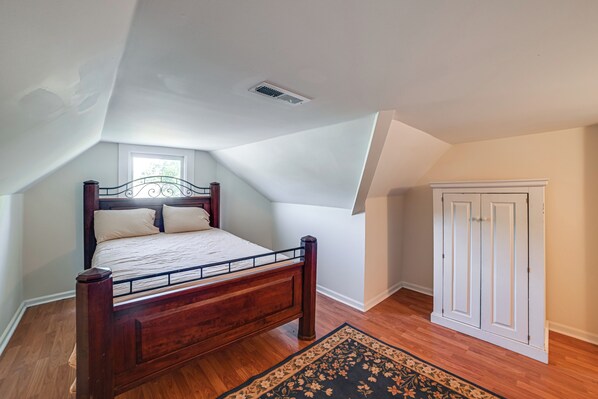 A bedroom with a wooden bed, a window, a door, and a ceiling vent. - Grand Victorian Home, Walk to Historic Town Square (Waverly)