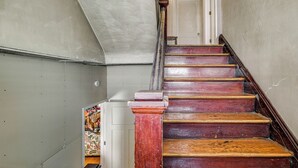Un escalier avec des marches en bois et une colonne rouge, menant à une porte.