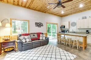 A modern kitchen with wooden cabinets, a central island with stools, and a dining area. - Hot Tub & Game Room: Lakefront Merrifield Retreat! (Merrifield)