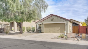 A residential house with a garage, a driveway, and a tree in the front yard. - 6 Mi to State Farm Stadium: Avondale Family Home! (Avondale)
