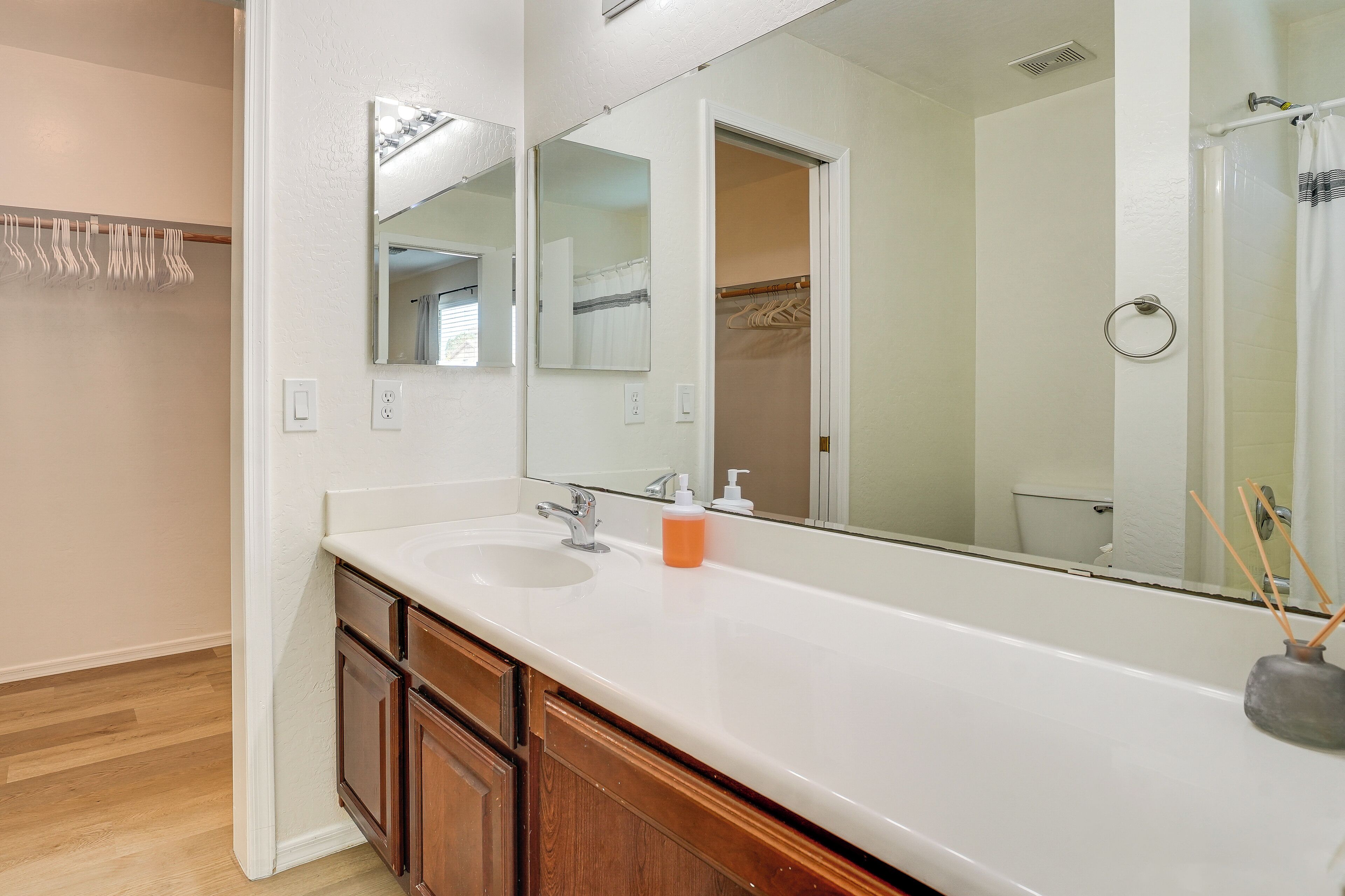 A bathroom with a large mirror, a white sink, wooden cabinets, and a shower curtain.