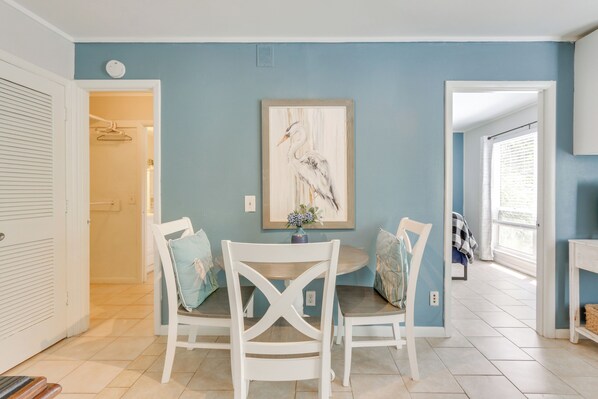 A dining area with a round table, white chairs, and a framed artwork on the wall. - Pool Access, Walk to Beach: Hilton Head Haven! (Hilton Head Island)