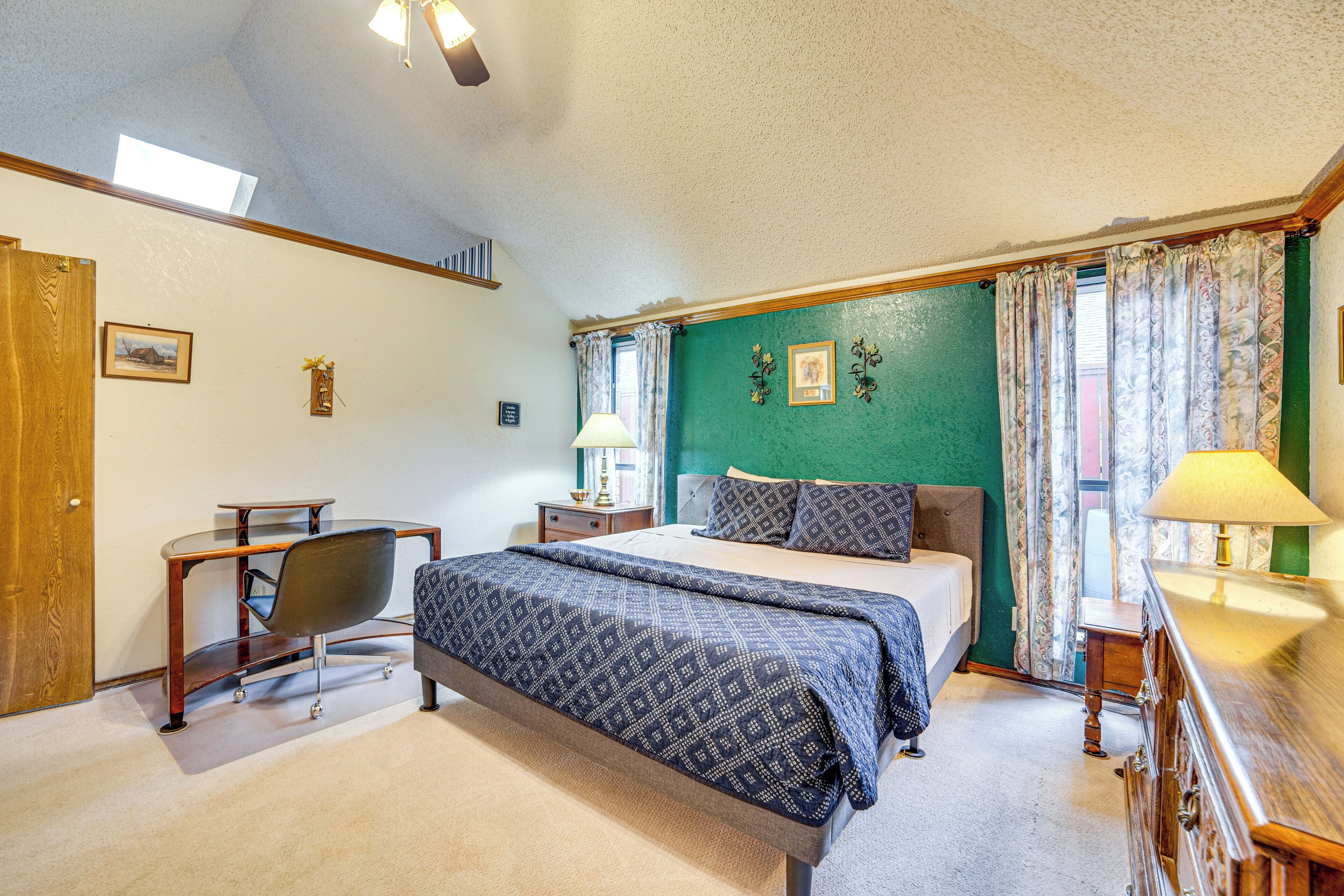A bedroom with a bed, bedside tables, a desk, and a chair.