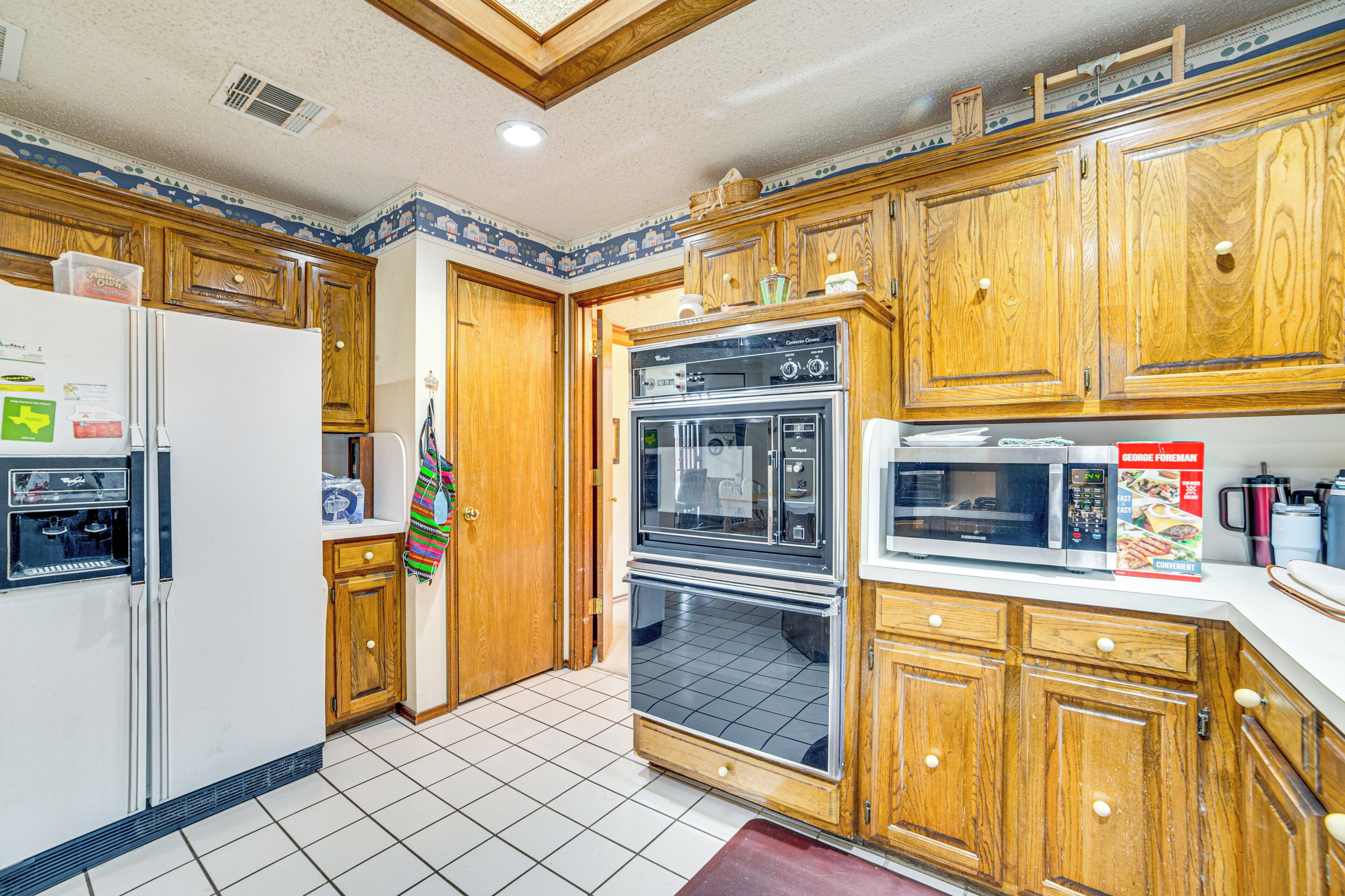 A kitchen with wooden cabinets, a refrigerator, an oven, and a microwave.