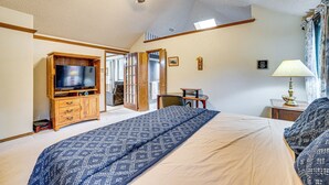 Une chambre à coucher comprenant un lit, un téléviseur, un ventilateur de plafond et un bureau avec une lampe.