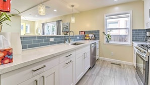 A modern kitchen with white cabinets, a stainless steel sink, and a built-in oven. - Sunny Oakland Retreat w/ Patio & Cute Garden! (Oakland)