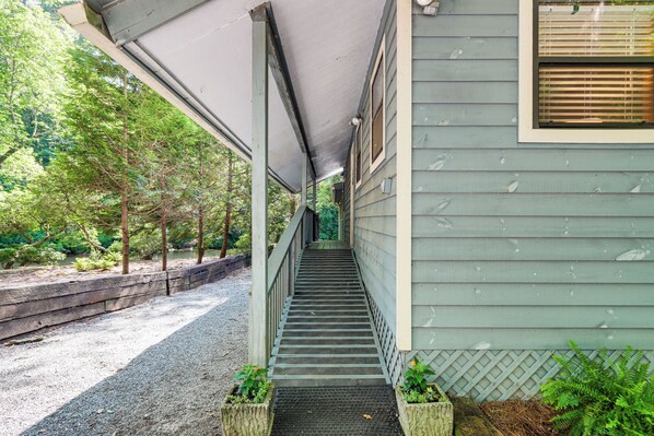 A covered outdoor staircase leading to a building with a lattice fence and greenery around. - Cartecay River Retreat w/ Yard & Screened Porch! (Ellijay)