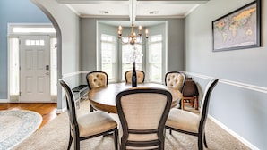 A dining room with a round table, six chairs, and a chandelier.