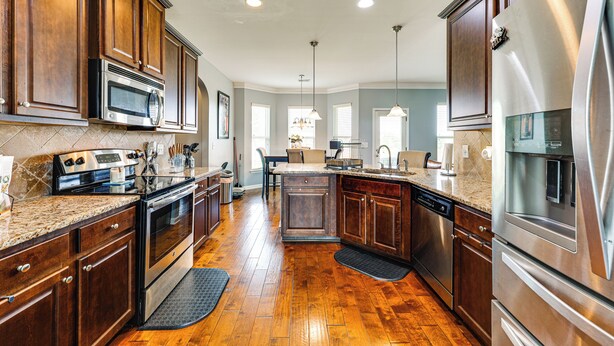 A modern kitchen with wooden cabinets, stainless steel appliances, and a granite countertop.