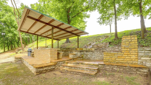 A covered outdoor area with stone steps leading up to a brick wall, surrounded by trees. - River Access & Private Deck: Mountain View Retreat (Mountain View)