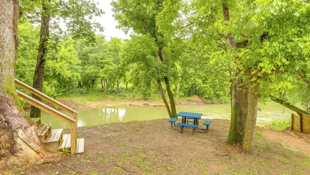 A picnic area with a table and benches, surrounded by trees and a body of water. - Swim On-site: Riverfront Studio in Mountain View! (Mountain View)