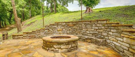 Un hogar de piedra rodeado por un muro de piedra en un área boscosa.