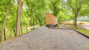 A wooden cabin with a red roof, surrounded by trees and a gravel path. - Swim On-site: Riverfront Studio in Mountain View! (Mountain View)