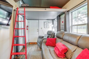 Un interior acogedor con un sofá de cuero, almohadas rojas, una escalera roja y una puerta con un letrero.