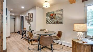 A dining area with a round table, four chairs, a lamp, and a painting on the wall.