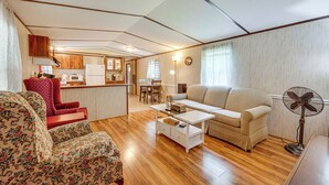 A compact living space with a sofa, armchair, and a small table. A kitchenette is visible in the background. - 5 Min Walk to Badin Lake: 3BD Home w/ Deck & BBQ (New London)