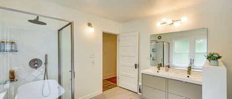 A modern bathroom with a glass-enclosed shower, a white sink, and a vanity with a large mirror.