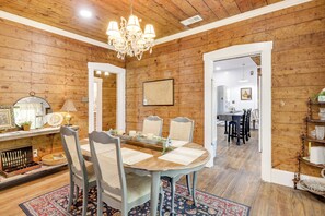 A dining area with a wooden table, four chairs, a chandelier, and a rug.