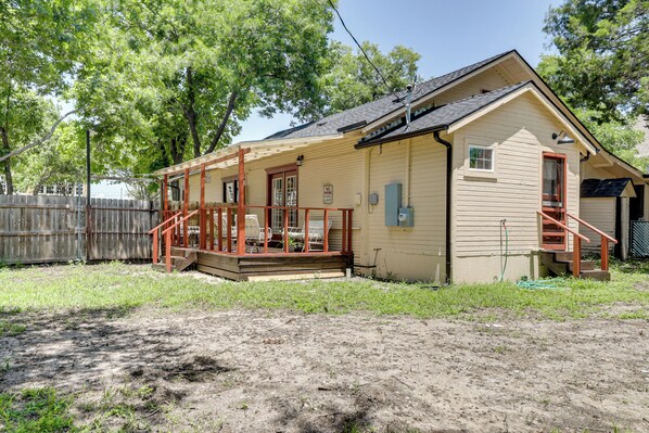 A single-story house with a porch, a small deck, and a fenced backyard.