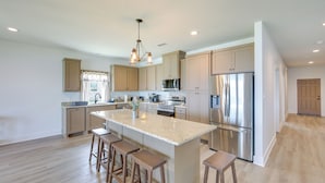 A spacious kitchen with a large island, stainless steel appliances, and wooden bar stools. - Lake Palestine Vacation Rental - Steps to Water! (Frankston)
