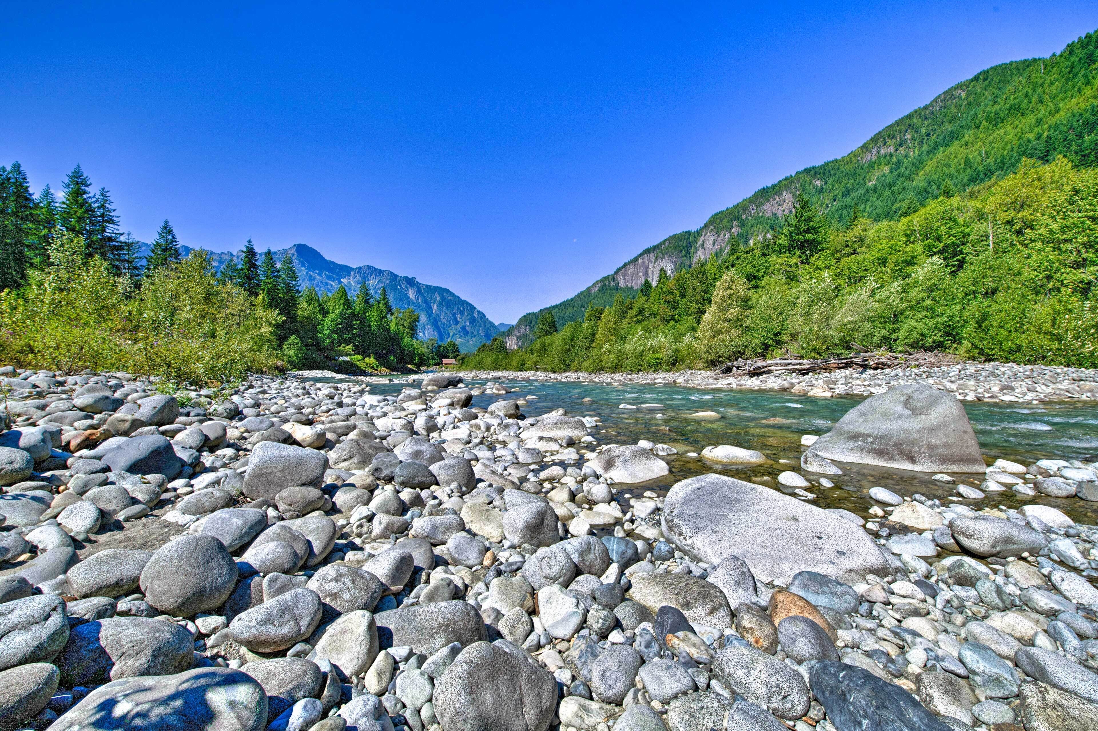 Een rivier met grote rotsen en een bergachtige achtergrond.