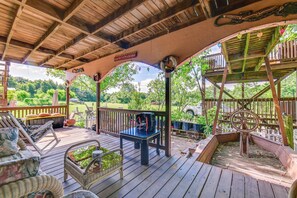 A covered outdoor deck with wooden furniture, a small table, and a decorative wheel. - 1 Mi to Boat Ramp: Lake Texoma Getaway w/ Deck (Kingston)