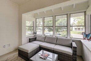 A living room with a sectional sofa, a glass coffee table, and large windows offering a view of the street. - 1 Mi to Beaches & Boardwalk: Asbury Park Retreat (Asbury Park)