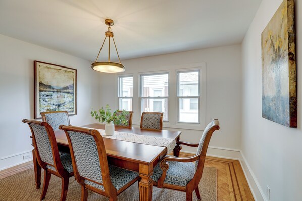 A dining room with a wooden table, six chairs, a chandelier, and artwork on the walls. - 1 Mi to Beaches & Boardwalk: Asbury Park Retreat (Asbury Park)