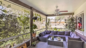 Un balcon abrité avec un canapé en osier, une petite table et des plantes en pot.