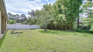 A backyard with a lawn, a wooden bench, and a white fence. - Family Home < 10 Mi to Flagler Beach: WFH Ready! (Palm Coast)
