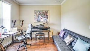 A living room with a piano, a couch, a desk with a computer, and a painting on the wall. - Family Home < 10 Mi to Flagler Beach: WFH Ready! (Palm Coast)