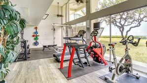 Ein modernes Fitnessstudio mit unterschiedlichen Trainingsgeräten, großen Fenstern und Zimmerpflanzen.
