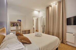 A neatly arranged bedroom with a bed, a bookshelf, a TV, and a wardrobe. - New Apartment Center of Paris (Paris)