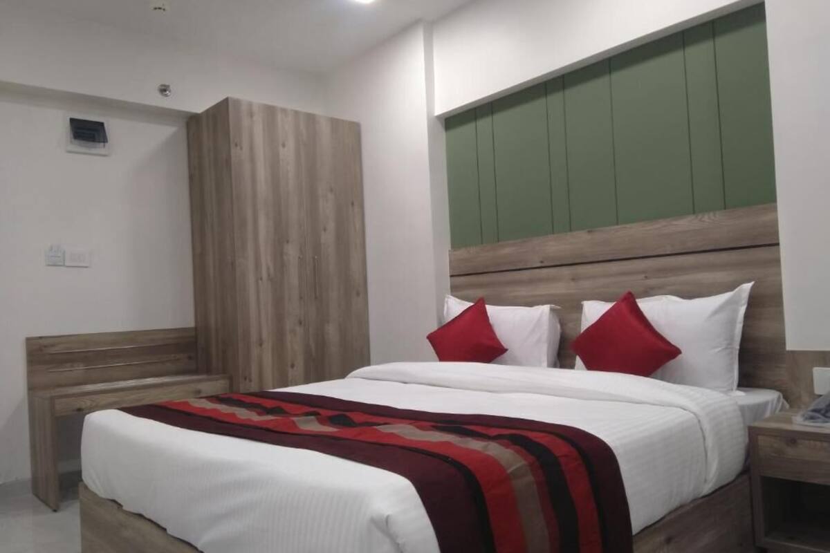 Una camera da letto con testiera in legno, un letto con biancheria da letto bianca e cuscini rossi, e un comodino con una lampada.