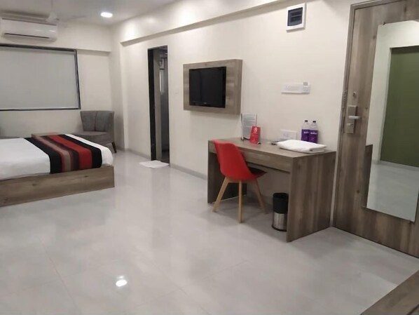 Una habitación de hotel moderna con una cama, un escritorio, una silla, un televisor y un cubo de basura.