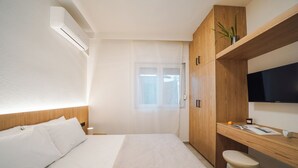 Une chambre d’hôtel moderne équipée d’un lit, d’un bureau en bois, d’une télévision et d’une fenêtre avec des rideaux.
