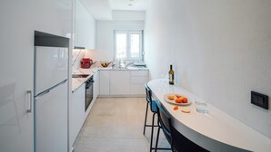 Une cuisine moderne avec des meubles blancs, un four encastré et une fenêtre au-dessus de l’évier.