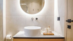 Une salle de bain moderne avec un miroir rond, un lavabo et un meuble-lavabo en bois.