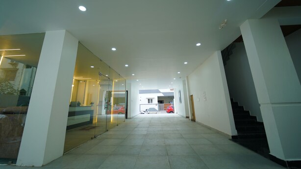 Een moderne hal met glazen wanden, inbouwverlichting en een trap.