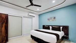 Een slaapkamer met een bed, een plafondventilator, een airconditioningapparaat, een kledingkast en een muur met kunstwerken.