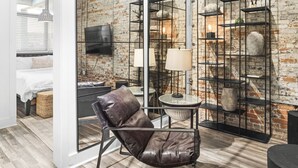 Ein modernes Wohnzimmer mit Ledersessel, Fernseher, Lampe und Backsteinwand.
