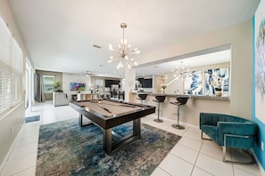 A modern living room with a pool table, bar area, and seating.