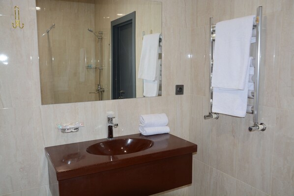 Un baño con un espejo grande, un lavabo marrón y un perchero con toallas dobladas.
