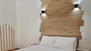 A modern bedroom with a wooden headboard, a large bed, and two wall-mounted lights.